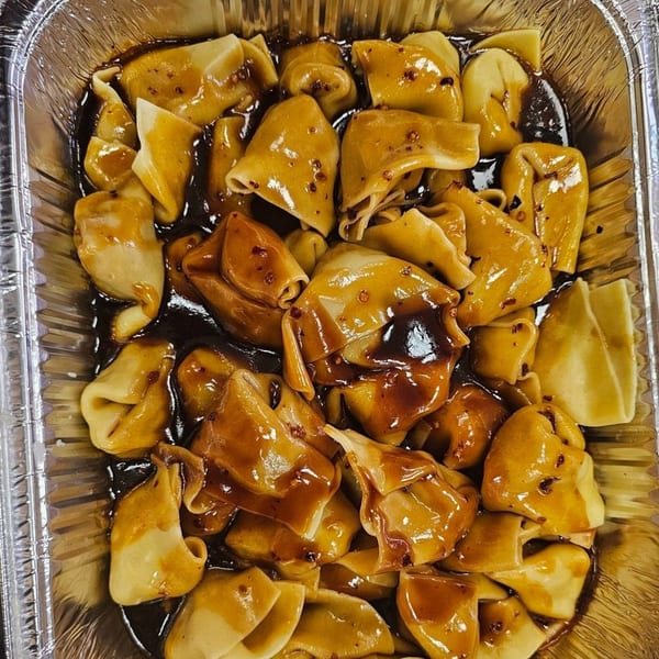 Mr Nosh's Chinese dumplings in a dark sauce, served in a foil container.
