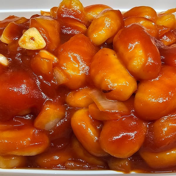 Close-up of Mr Nosh's sweet and sour chicken balls with garlic and onions.