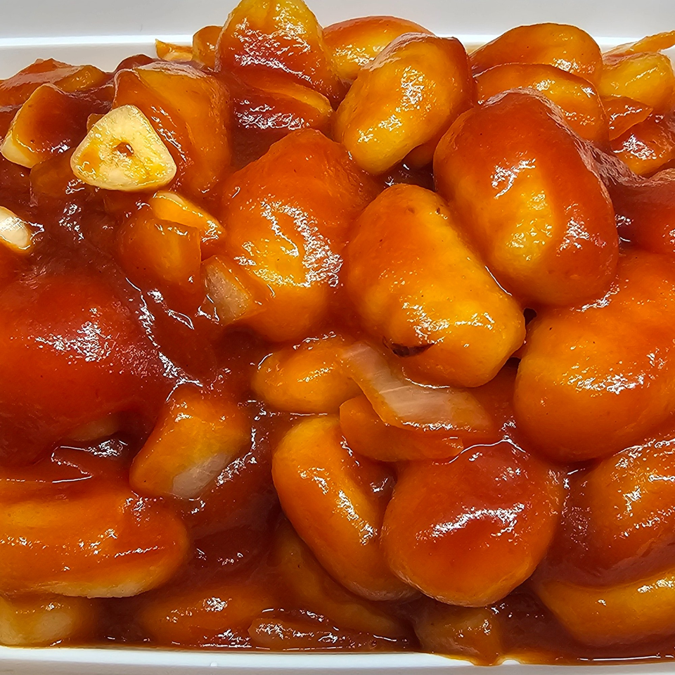 Close-up of Mr Nosh's sweet and sour chicken balls with garlic and onions.