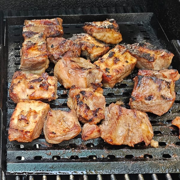 Close-up of Mr Nosh's grilled Chinese-style beef cubes with char marks on a black grill.